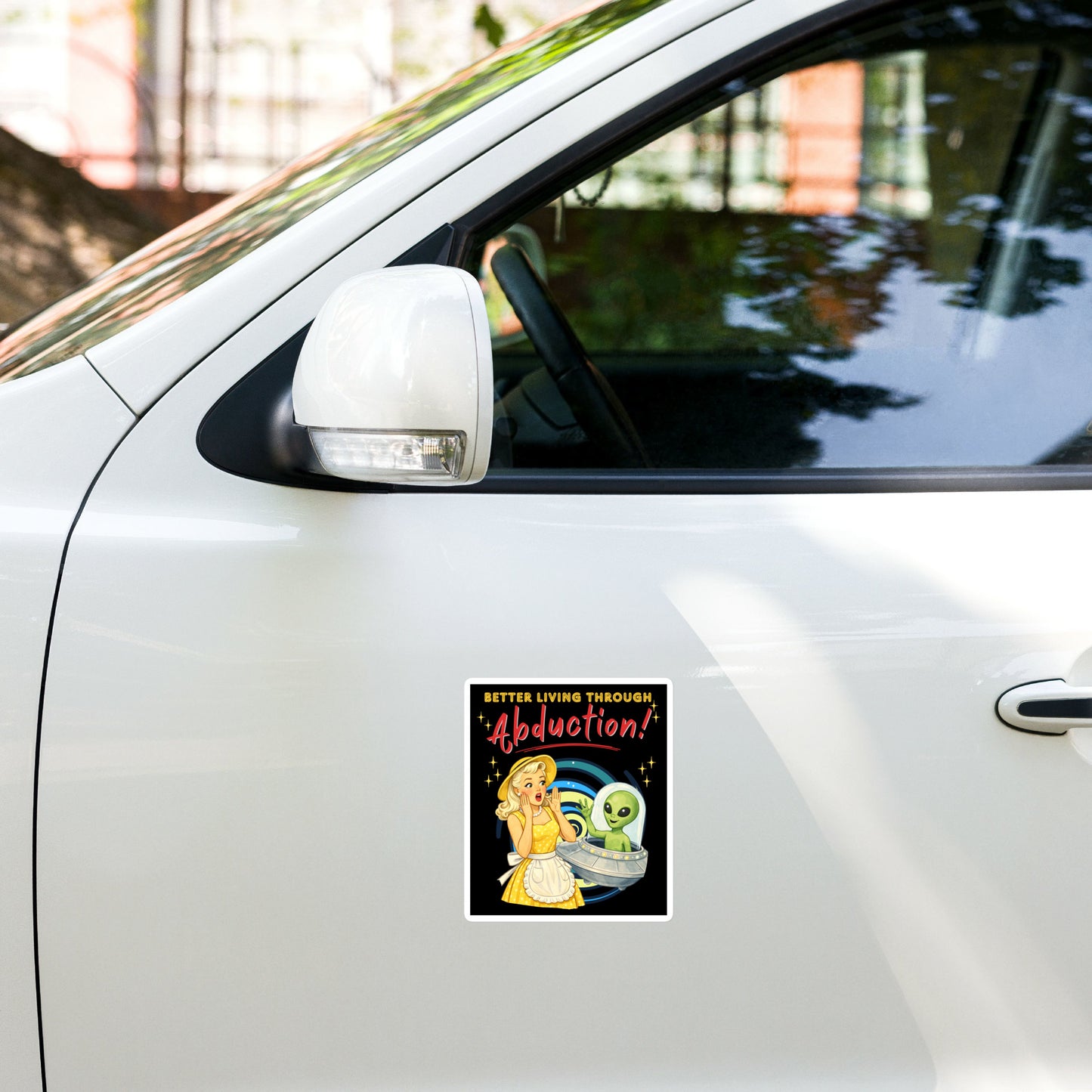 Better Living Through Abduction vinyl decal — vintage 1950s retro blonde housewife in yellow polka dot dress reacting with delight to a friendly green alien waving from a silver saucer on black background, satin finish waterproof sticker by Cinderpoint Studios
