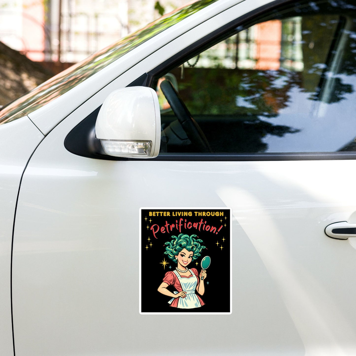 Better Living Through Petrification vinyl decal — vintage 1950s retro Medusa housewife with styled snake hair holding a hand mirror and smiling confidently in pearls and apron on black background, satin finish waterproof sticker by Cinderpoint Studios