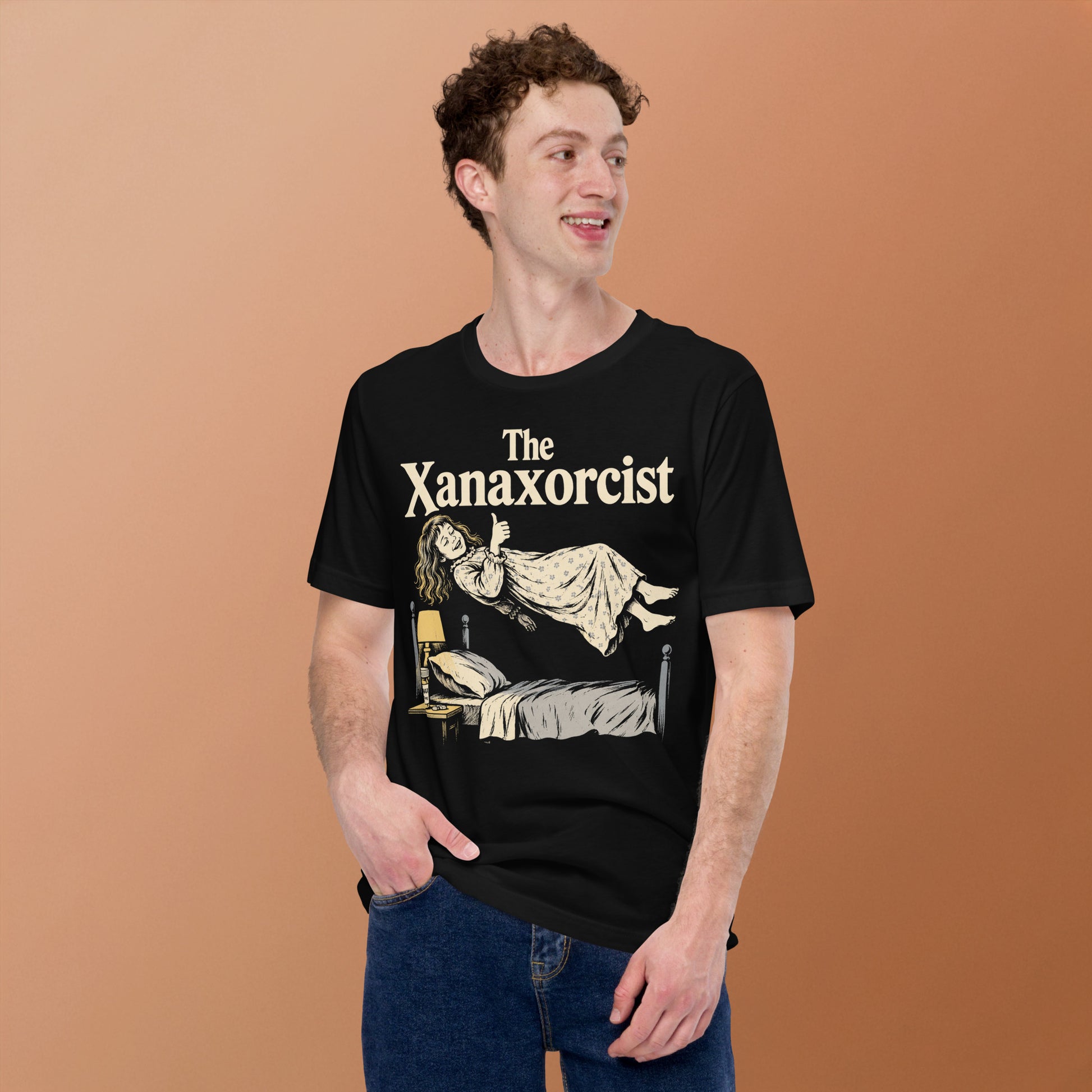 A retro horror-style graphic t-shirt featuring "The Xanaxorcist" in classic cinematic lettering with a stylized, eerie parody of the iconic exorcism scene.