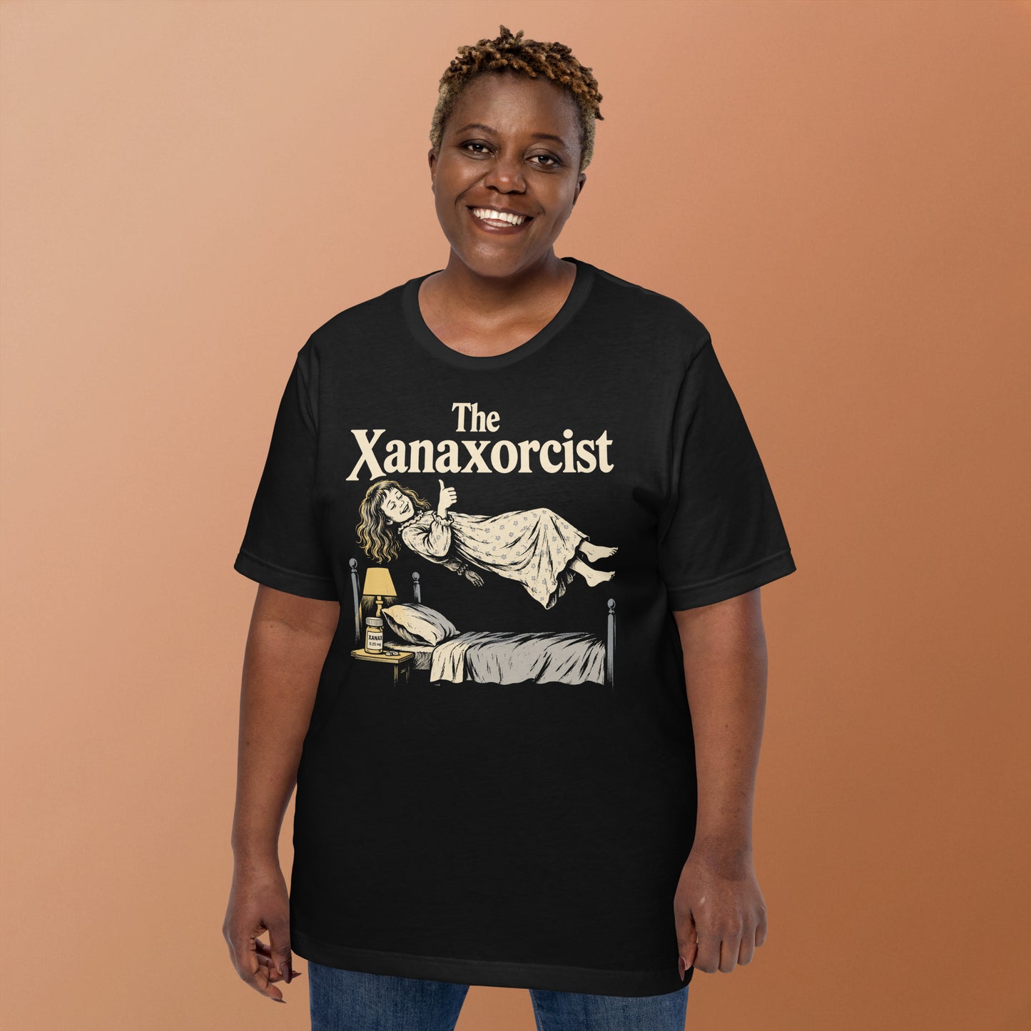 A retro horror-style graphic t-shirt featuring "The Xanaxorcist" in classic cinematic lettering with a stylized, eerie parody of the iconic exorcism scene.