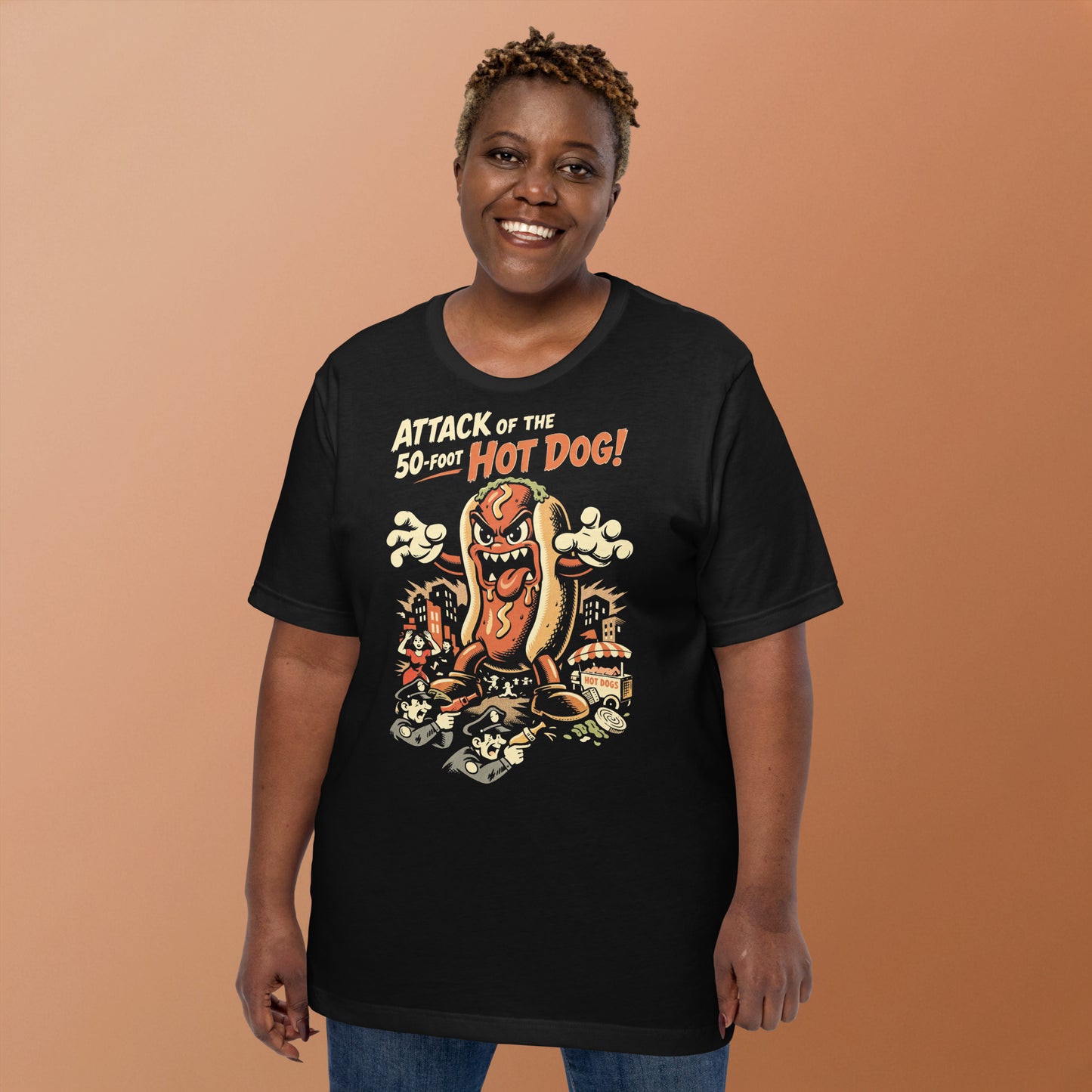 A retro B-movie style graphic t-shirt featuring a giant 50-foot hot dog attacking a vintage city skyline, with campy horror-themed cinematic lettering.