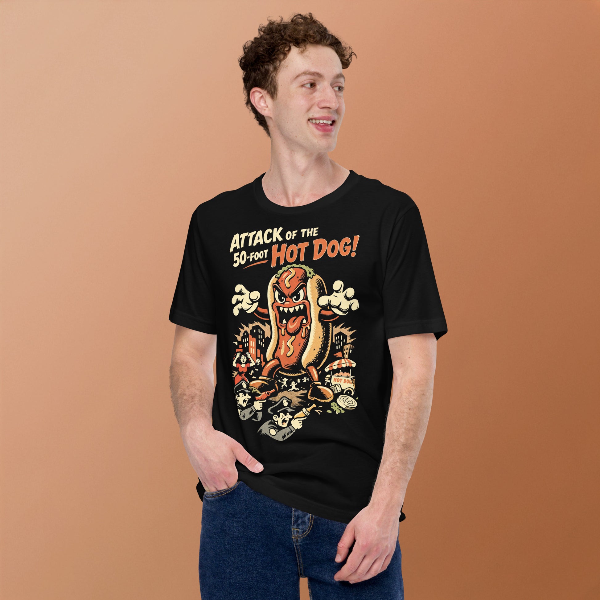 A retro B-movie style graphic t-shirt featuring a giant 50-foot hot dog attacking a vintage city skyline, with campy horror-themed cinematic lettering.