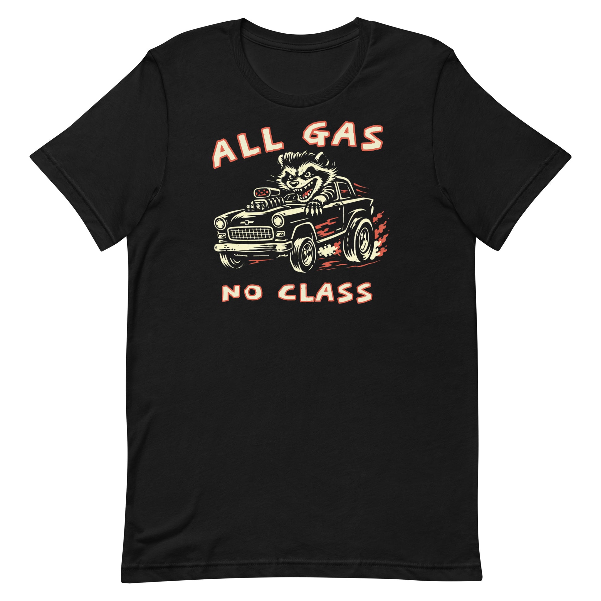 A top-down photograph of a premium black t-shirt on a weathered wooden workbench. The shirt features a two-color distressed graphic of a pompadoured raccoon driving a high-performance rat rod with the text "ALL GAS NO CLASS."