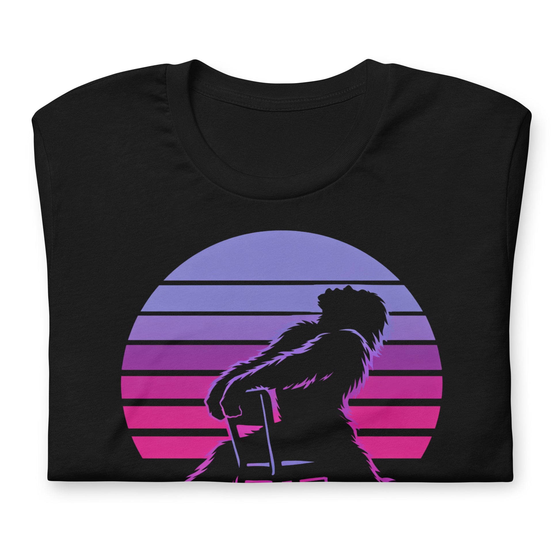 A retro graphic t-shirt featuring the cryptid Bigfoot in the iconic Flashdance chair-pose silhouette against a vibrant 1980s-style sunset.