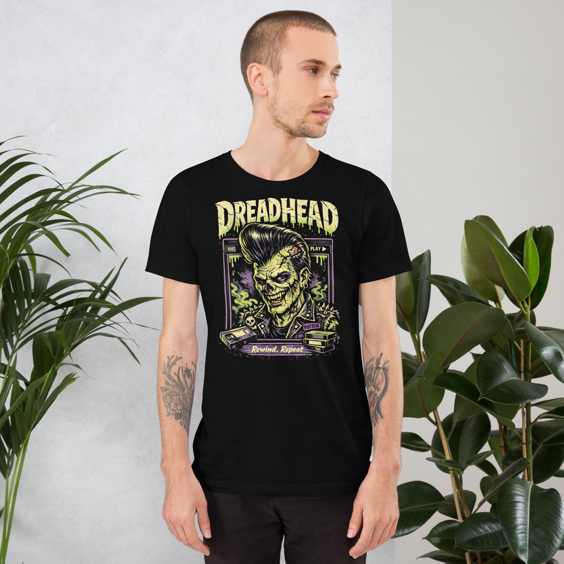 A retro 80s horror-style graphic on a black t-shirt featuring a zombie greaser with a pompadour and "Dreadhead" and "Rewind Repeat" in distressed VHS-style lettering.