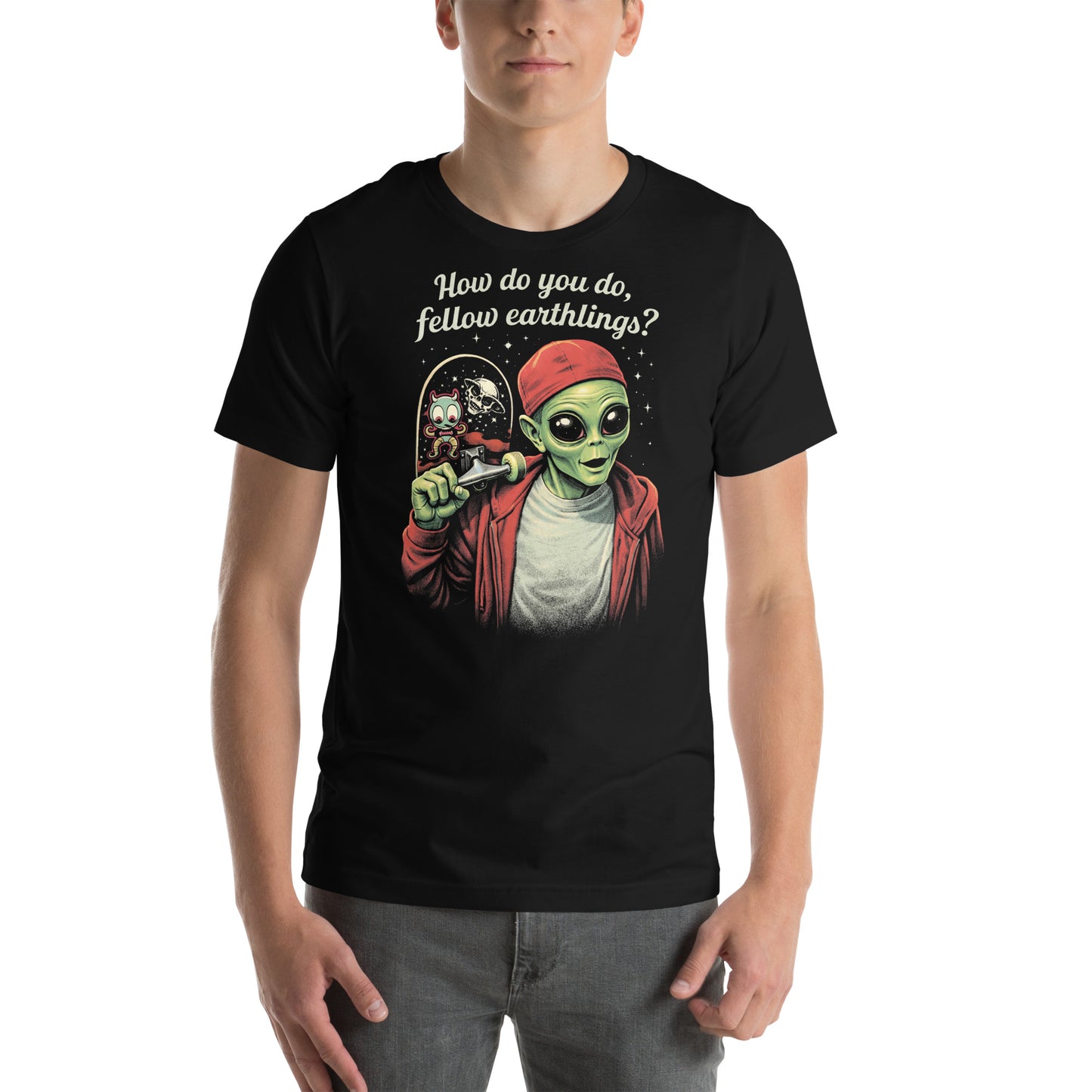 A retro-style graphic on a black t-shirt featuring a green alien on a skateboard, wearing a red hat and holding a skateboard, with the text "FELLOW EARTHLINGS.