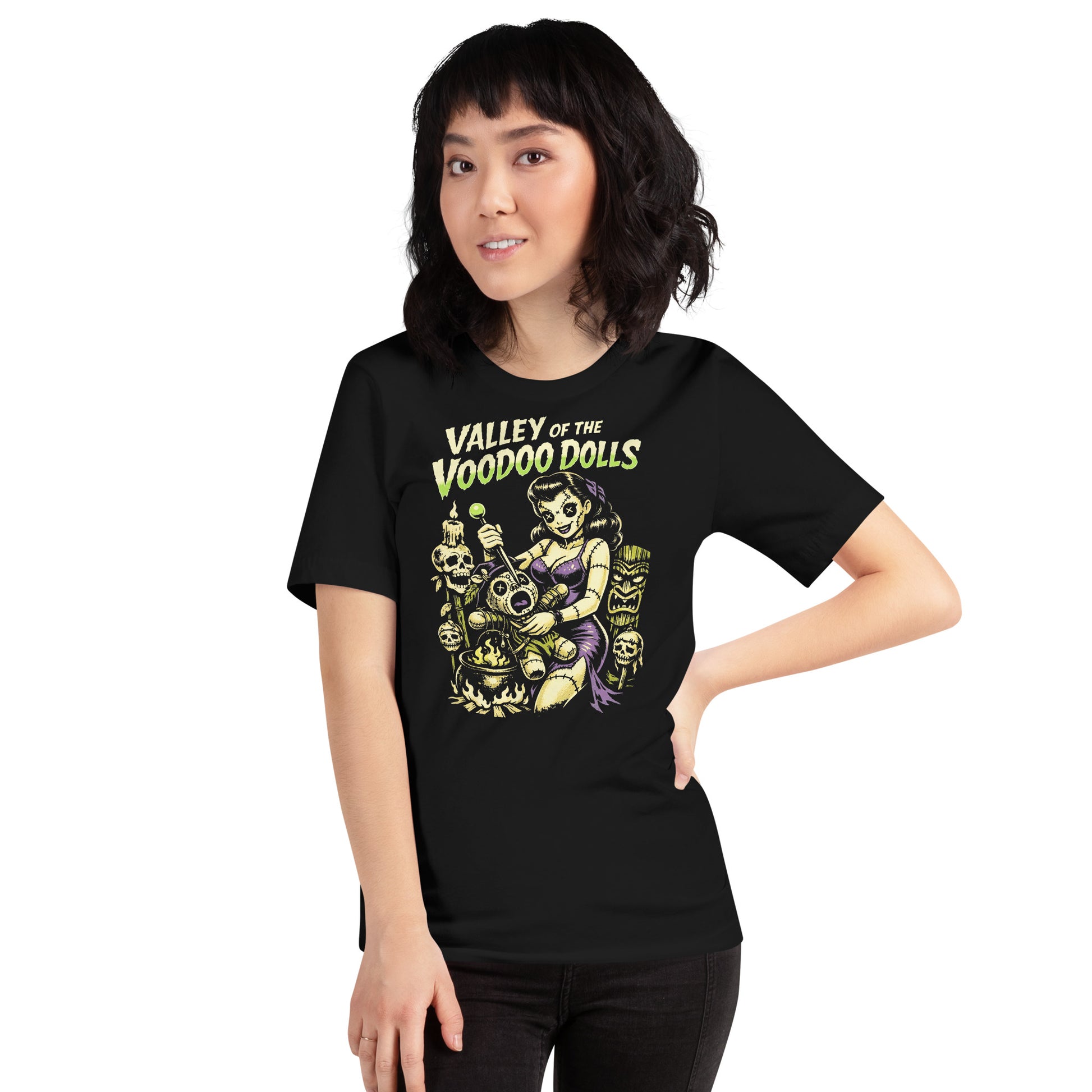 A retro-style graphic on a black t-shirt featuring a stylized pinup girl voodoo doll turning the tables on a medicine man in a vibrant, gritty Tiki-horror aesthetic
