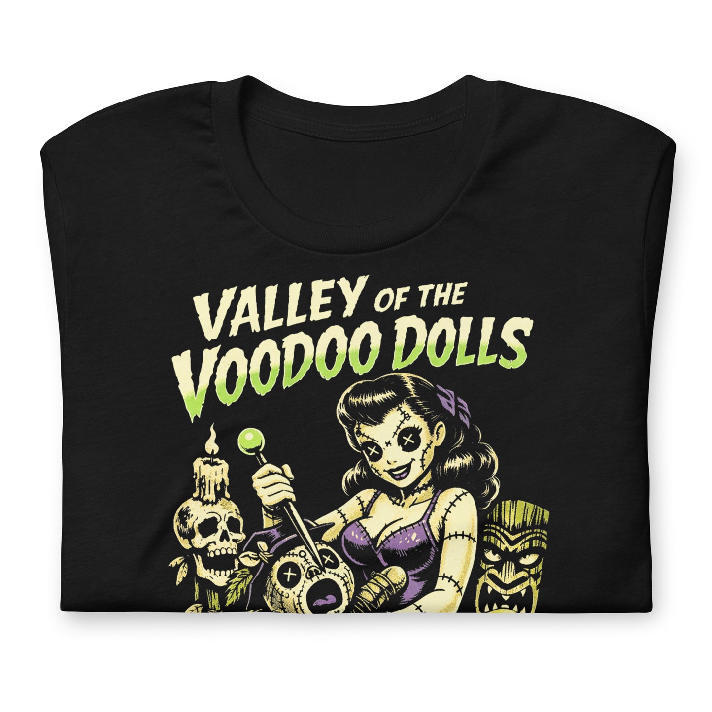 A retro-style graphic on a black t-shirt featuring a stylized pinup girl voodoo doll turning the tables on a medicine man in a vibrant, gritty Tiki-horror aesthetic