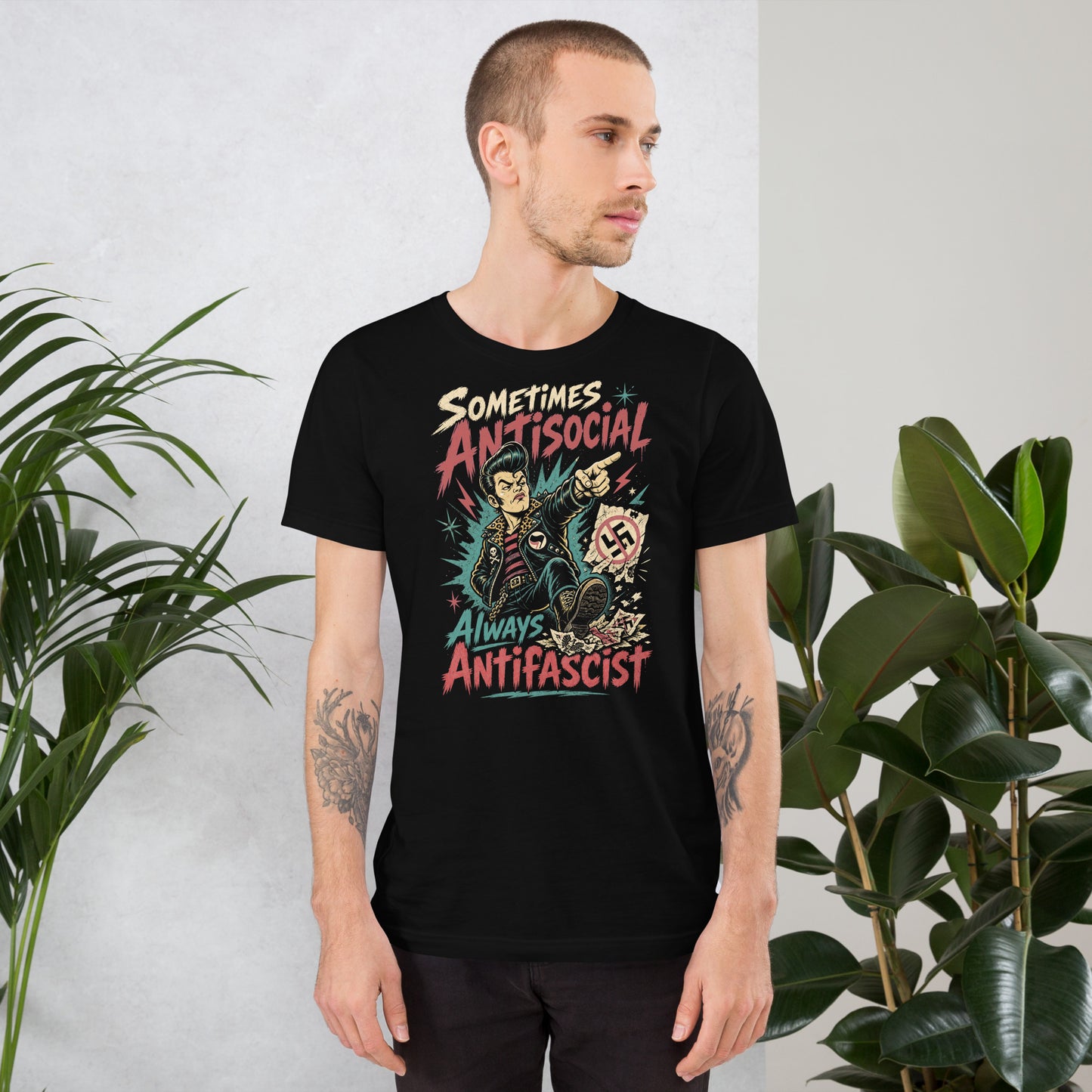 A gritty, lowbrow illustration on a black t-shirt of a pompadoured greaser in a leopard-print lined leather jacket, kicking over hate symbols. Text reads 'Sometimes Antisocial Always Antifascist' in a distressed punk-style font.