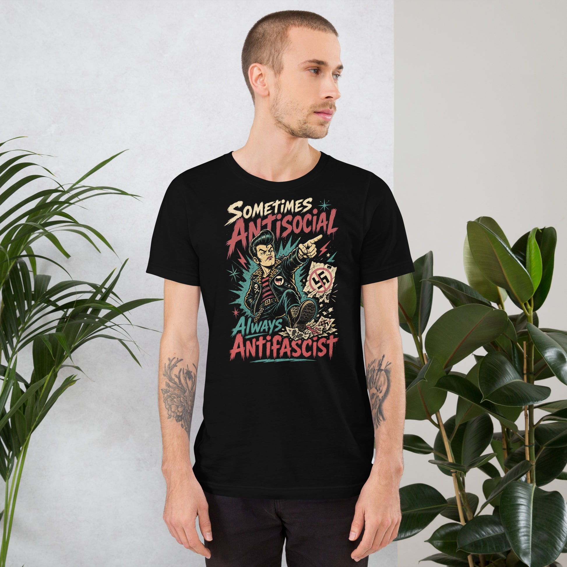 A gritty, lowbrow illustration on a black t-shirt of a pompadoured greaser in a leopard-print lined leather jacket, kicking over hate symbols. Text reads 'Sometimes Antisocial Always Antifascist' in a distressed punk-style font.