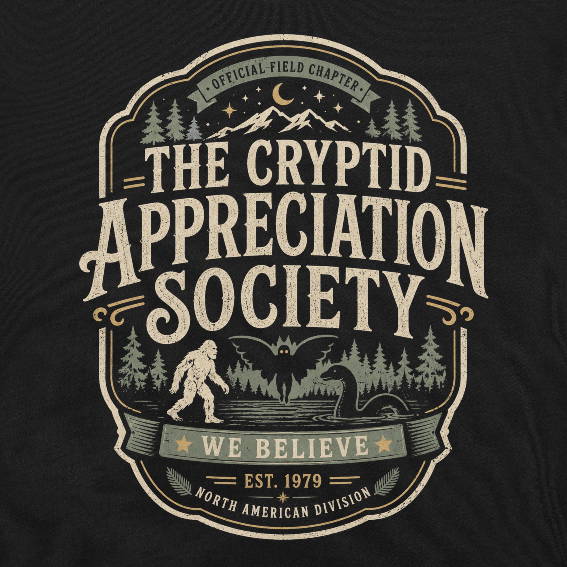 Black graphic tee featuring original Cinderpoint Studios artwork for The Cryptid Appreciation Society, a retro cryptid badge design with Sasquatch, Mothman, a Nessie-style lake creature, forest, mountains, moon, stars, and We Believe text.