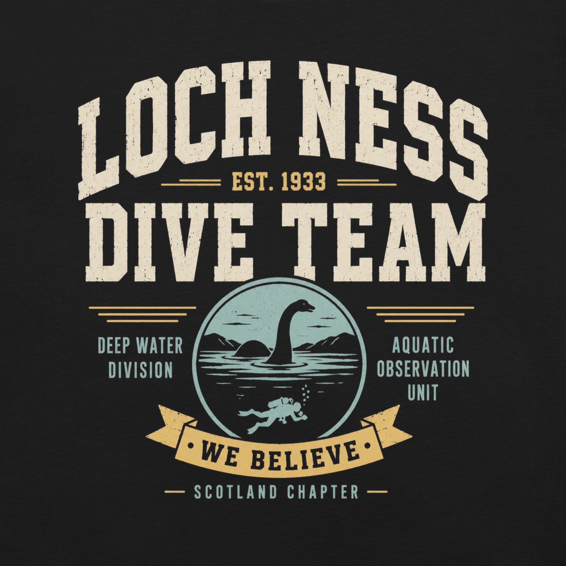 Black graphic tee featuring original Cinderpoint Studios artwork for Loch Ness Dive Team, a retro cryptid design with bold varsity lettering, a Nessie-style lake monster, diver, water scene, and text including Deep Water Division, Aquatic Observation Unit, We Believe, and Scotland Chapter.