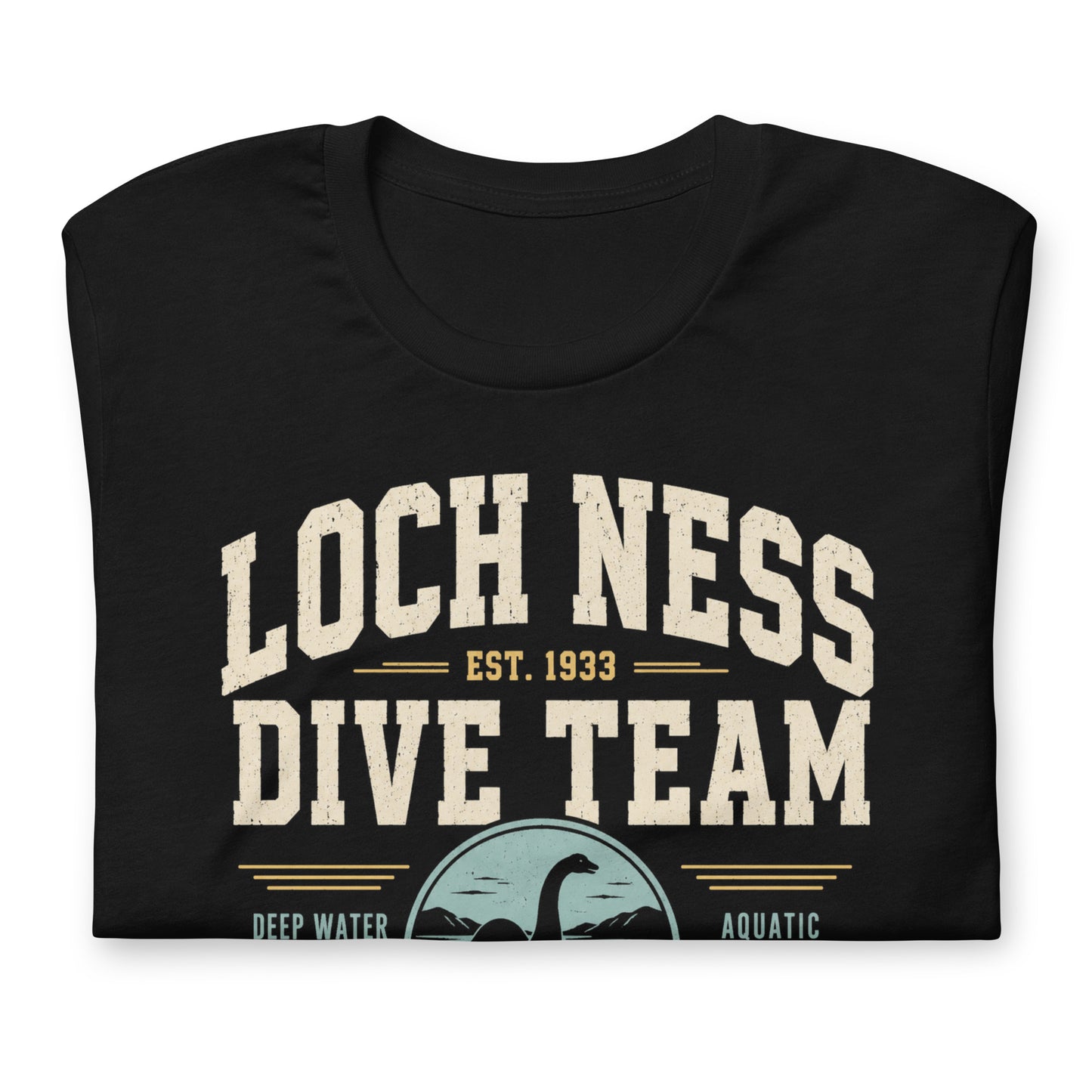 Black graphic tee featuring original Cinderpoint Studios artwork for Loch Ness Dive Team, a retro cryptid design with bold varsity lettering, a Nessie-style lake monster, diver, water scene, and text including Deep Water Division, Aquatic Observation Unit, We Believe, and Scotland Chapter.
