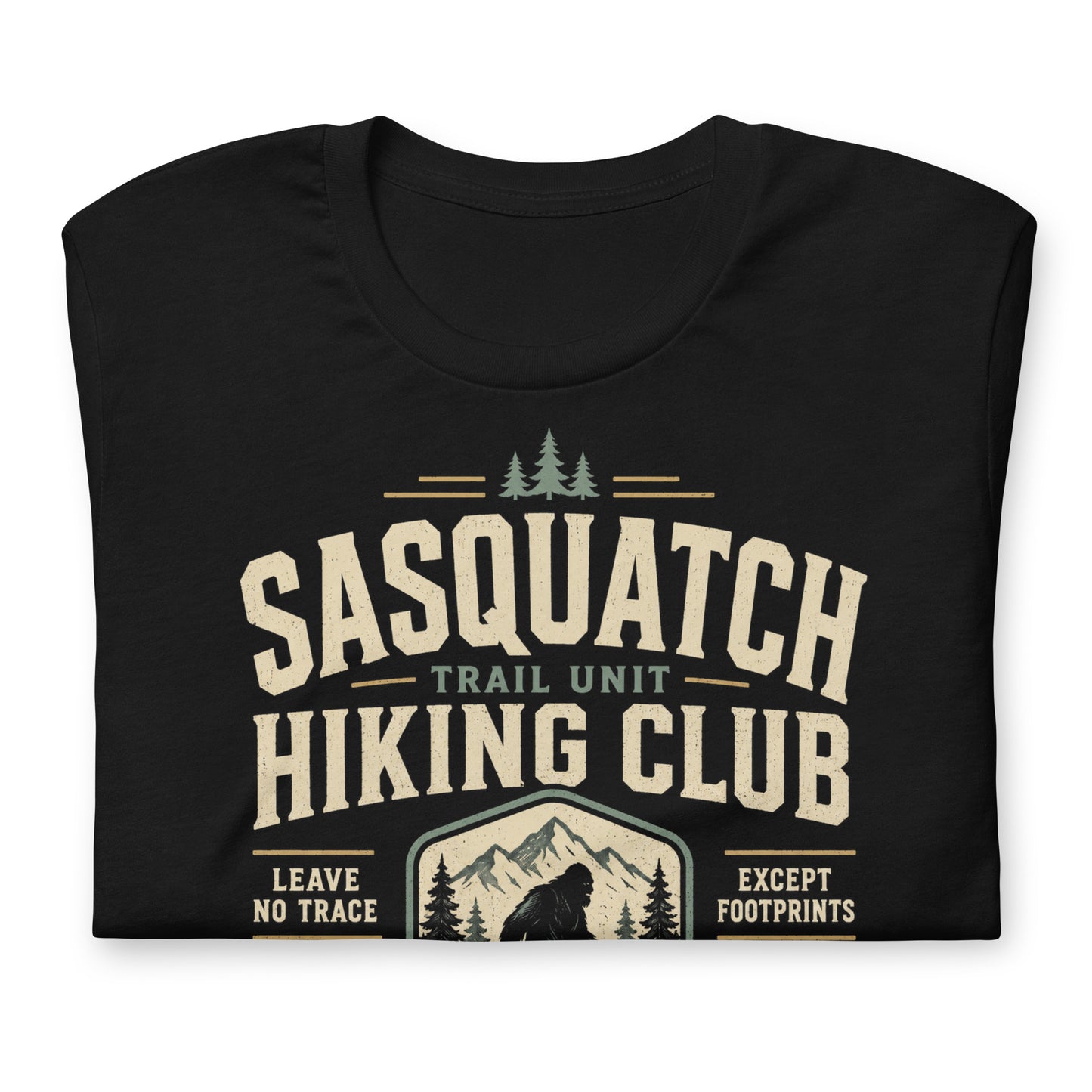 Close-up of the Sasquatch Hiking Club original Cinderpoint Studios artwork printed on a black tee, showing distressed retro lettering, Sasquatch silhouette, mountain scenery, pine trees, footprints, and Official Forest Division details.