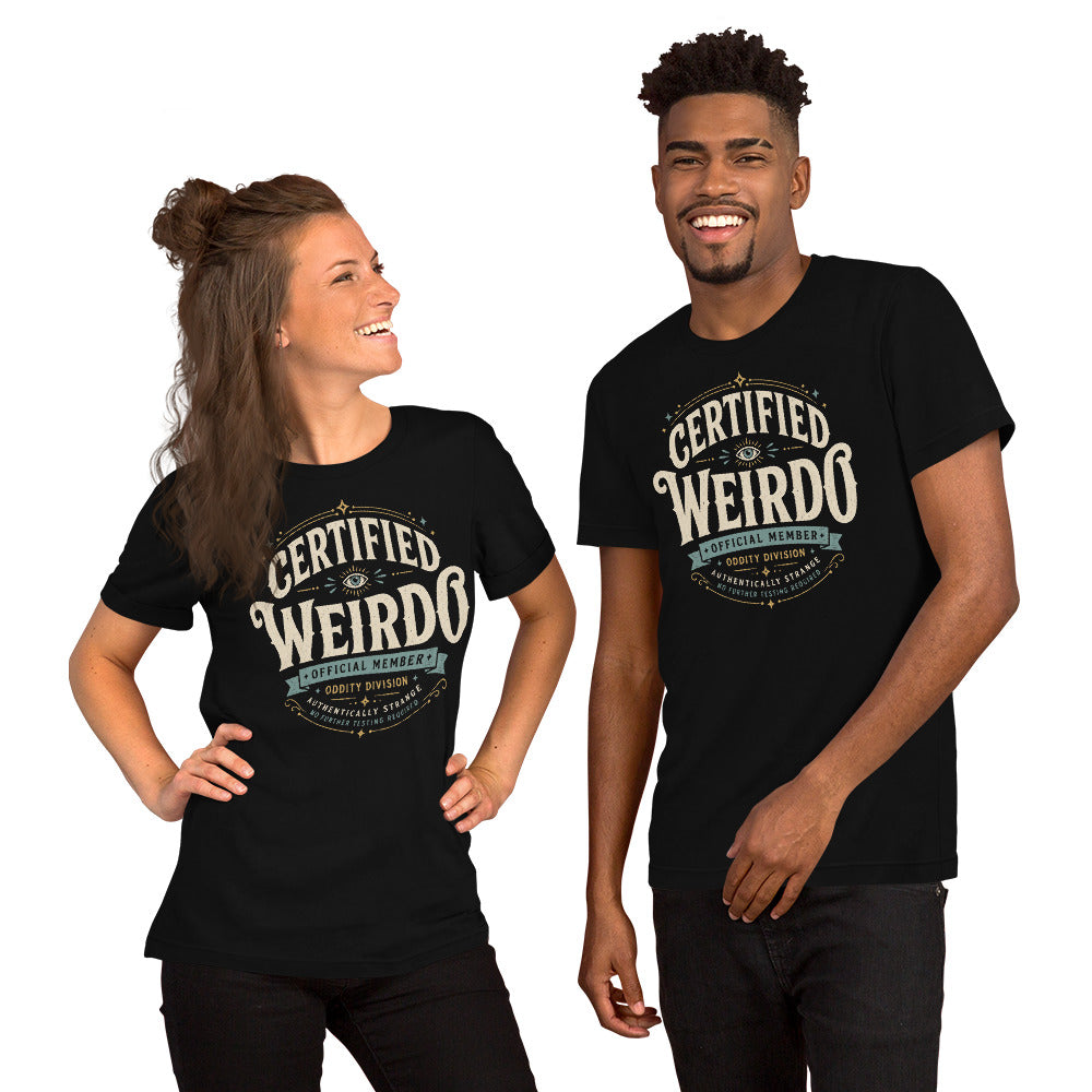 A man and woman wearing black graphic tees with the Certified Weirdo artwork by Cinderpoint Studios, styled as a boutique retro weirdo shirt with all-seeing eye details, Oddity Division text, and Authentically Strange wording.