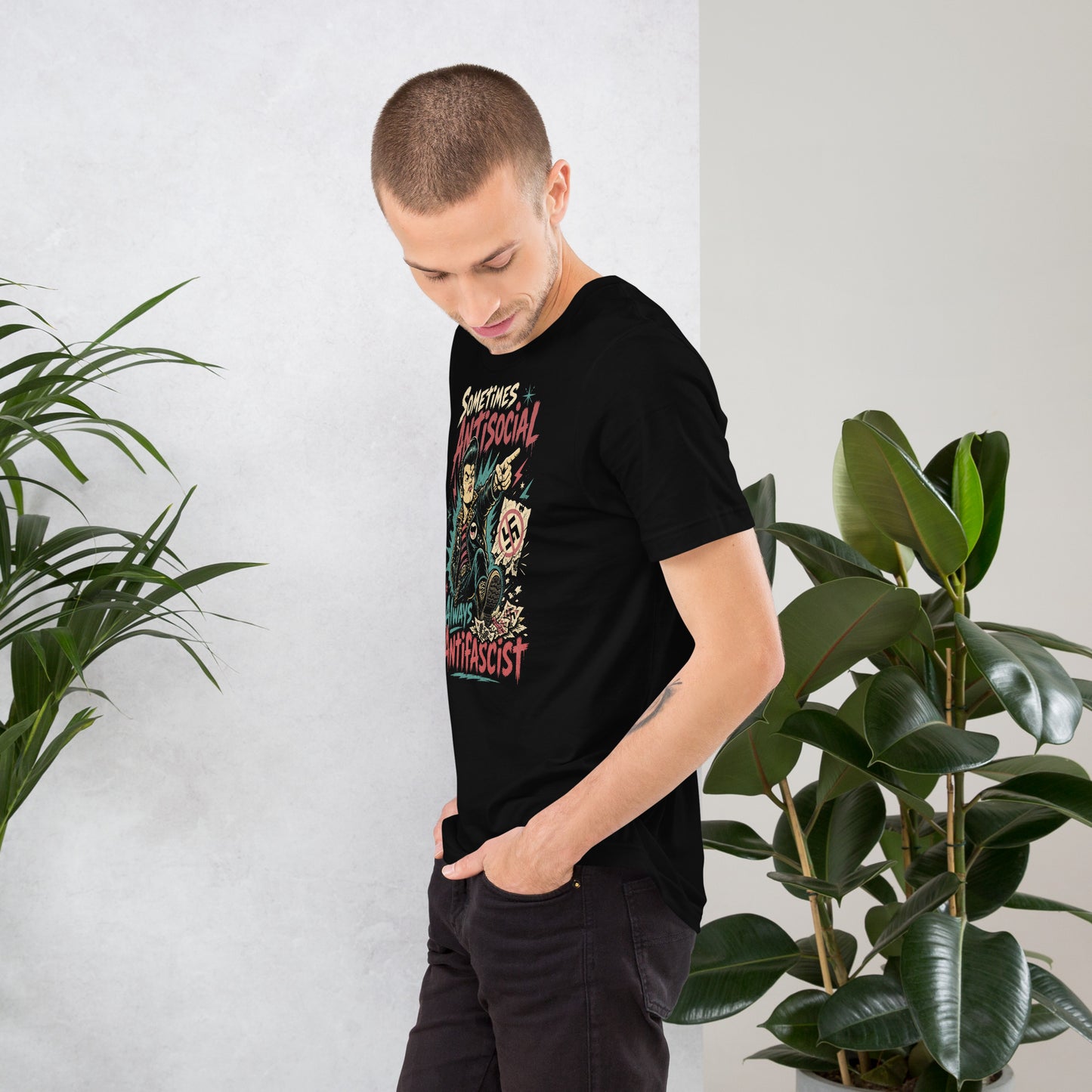A gritty, lowbrow illustration on a black t-shirt of a pompadoured greaser in a leopard-print lined leather jacket, kicking over hate symbols. Text reads 'Sometimes Antisocial Always Antifascist' in a distressed punk-style font.