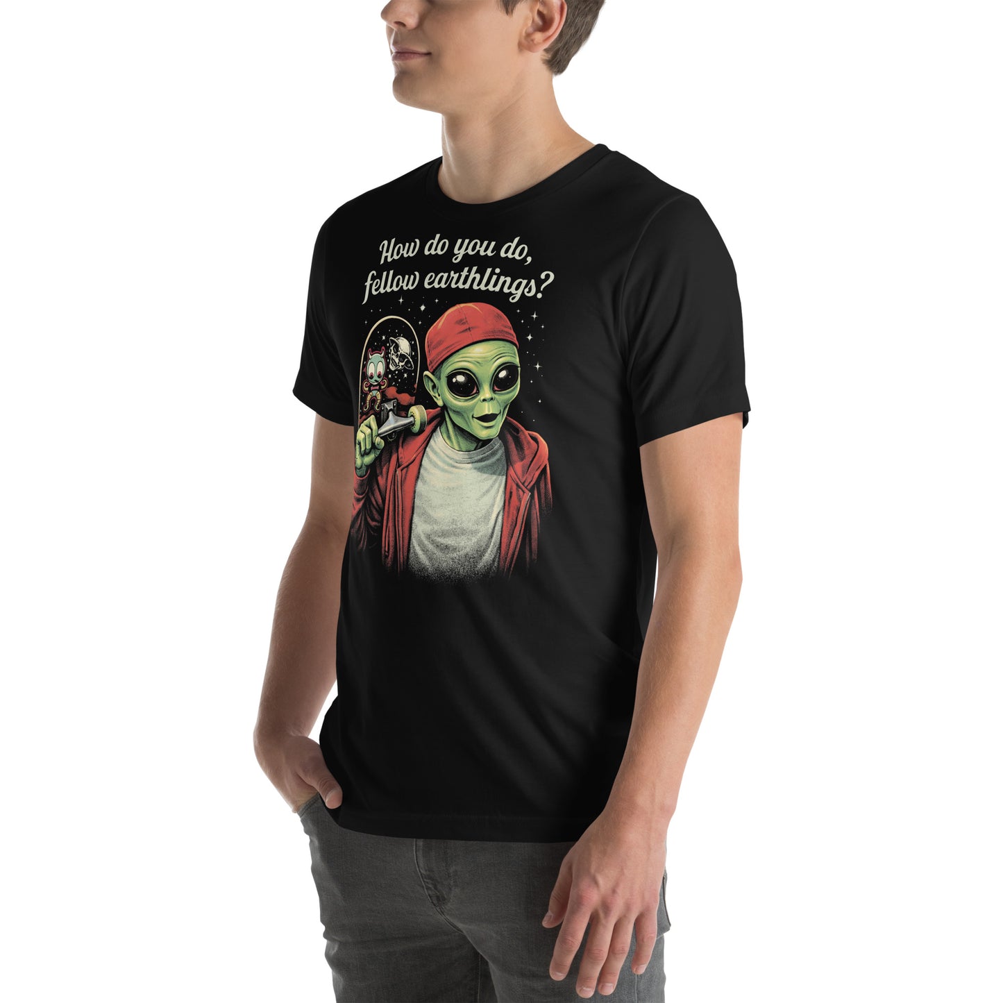 A retro-style graphic on a black t-shirt featuring a green alien on a skateboard, wearing a red hat and holding a skateboard, with the text "FELLOW EARTHLINGS.