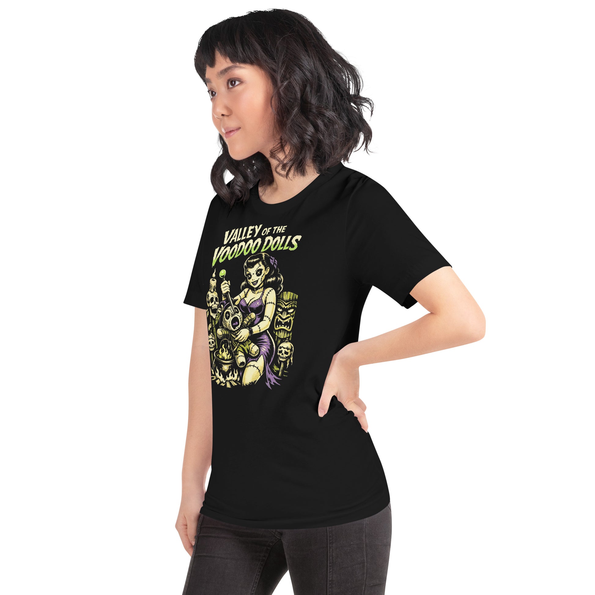 A retro-style graphic on a black t-shirt featuring a stylized pinup girl voodoo doll turning the tables on a medicine man in a vibrant, gritty Tiki-horror aesthetic