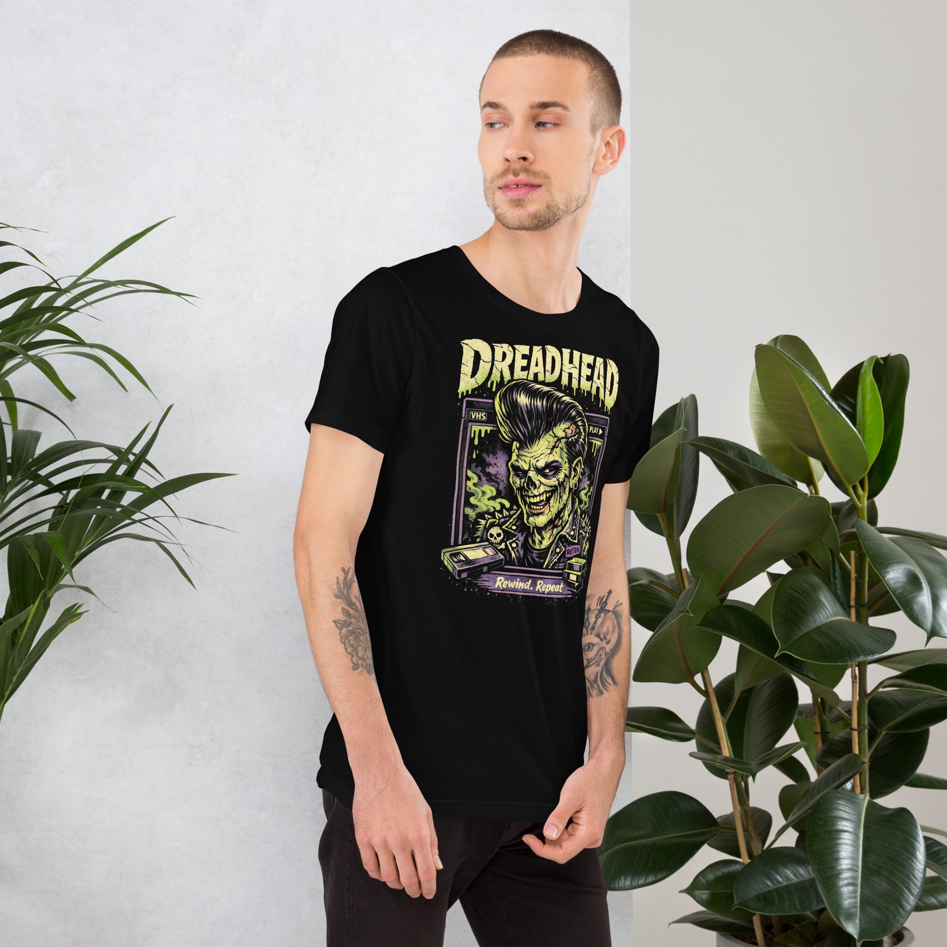 A retro 80s horror-style graphic on a black t-shirt featuring a zombie greaser with a pompadour and "Dreadhead" and "Rewind Repeat" in distressed VHS-style lettering.