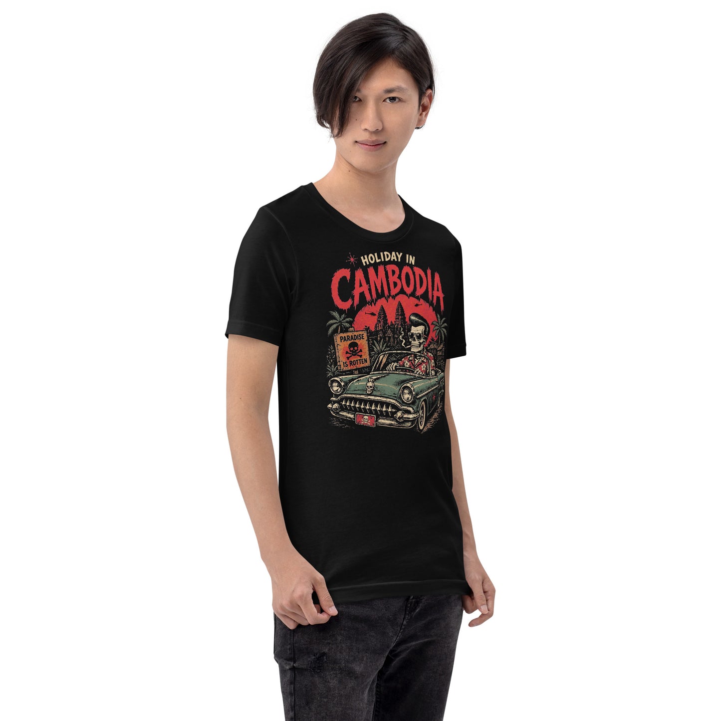 A detailed lowbrow graphic on a black t-shirt featuring a skeleton with a pompadour driving a 1955 Chevy convertible. The background shows Angkor Wat under a red sun with helicopters, and a sign that reads 'Paradise is Rotten'.