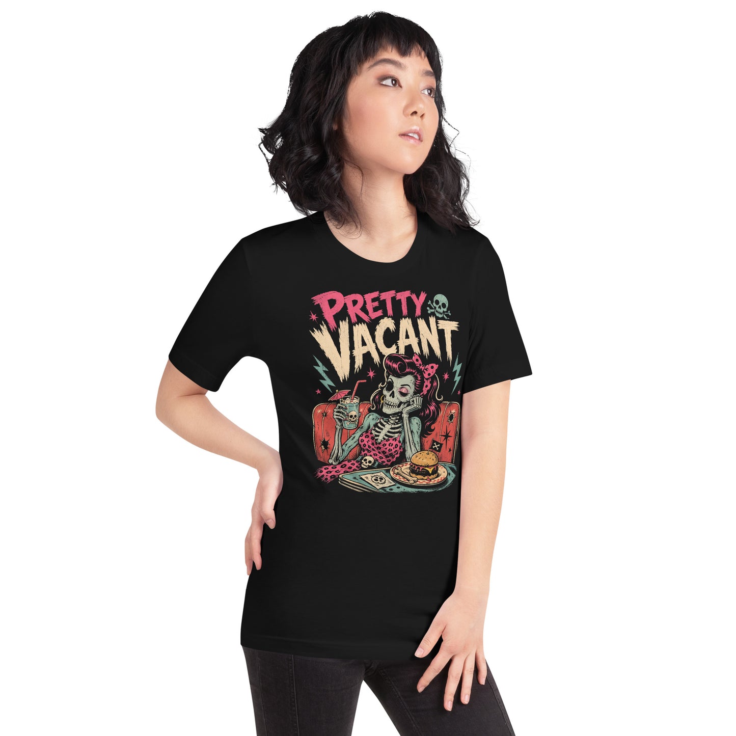 A retro-style graphic on a black t-shirt of a female skeleton pinup with pink hair in a diner booth, holding a skull-themed milkshake next to a burger with a crossbones flag.