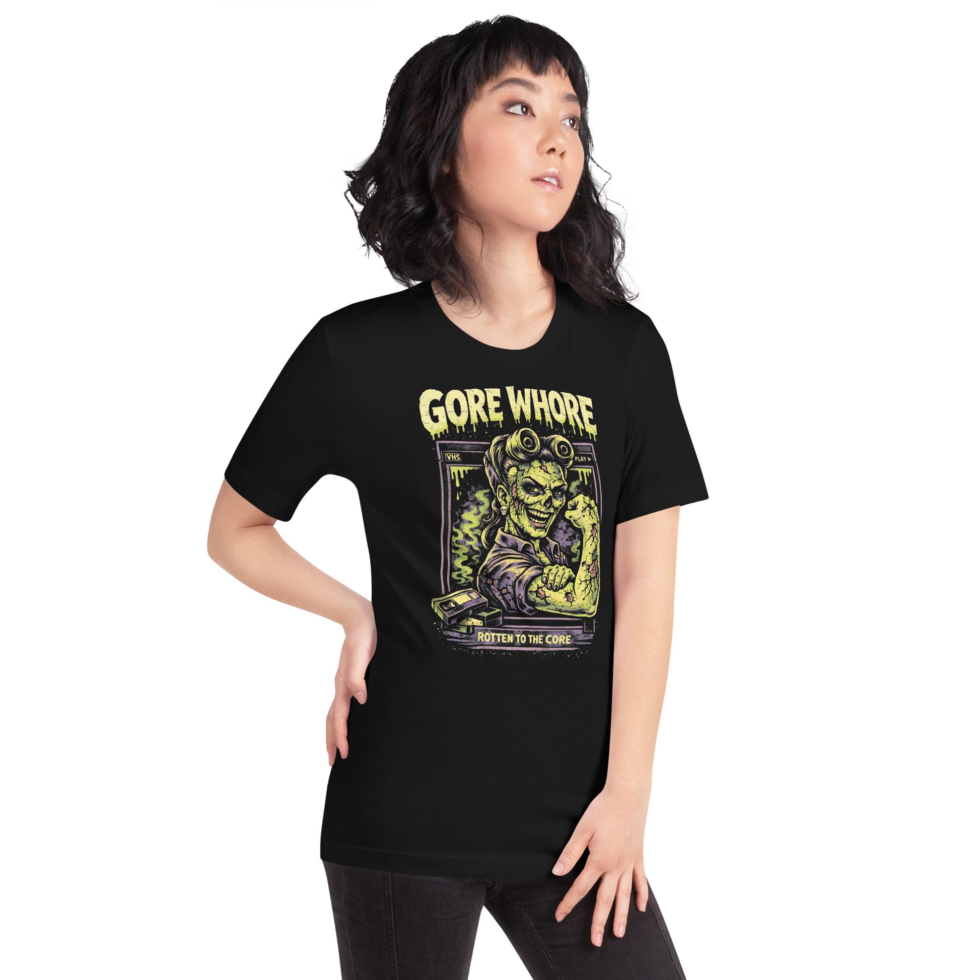 A retro 80s horror-style graphic on a black t-shirt featuring a stylized zombie pin-up girl with "Gore Whore" and "Rotten to the Core" in distressed, slasher-flick lettering.