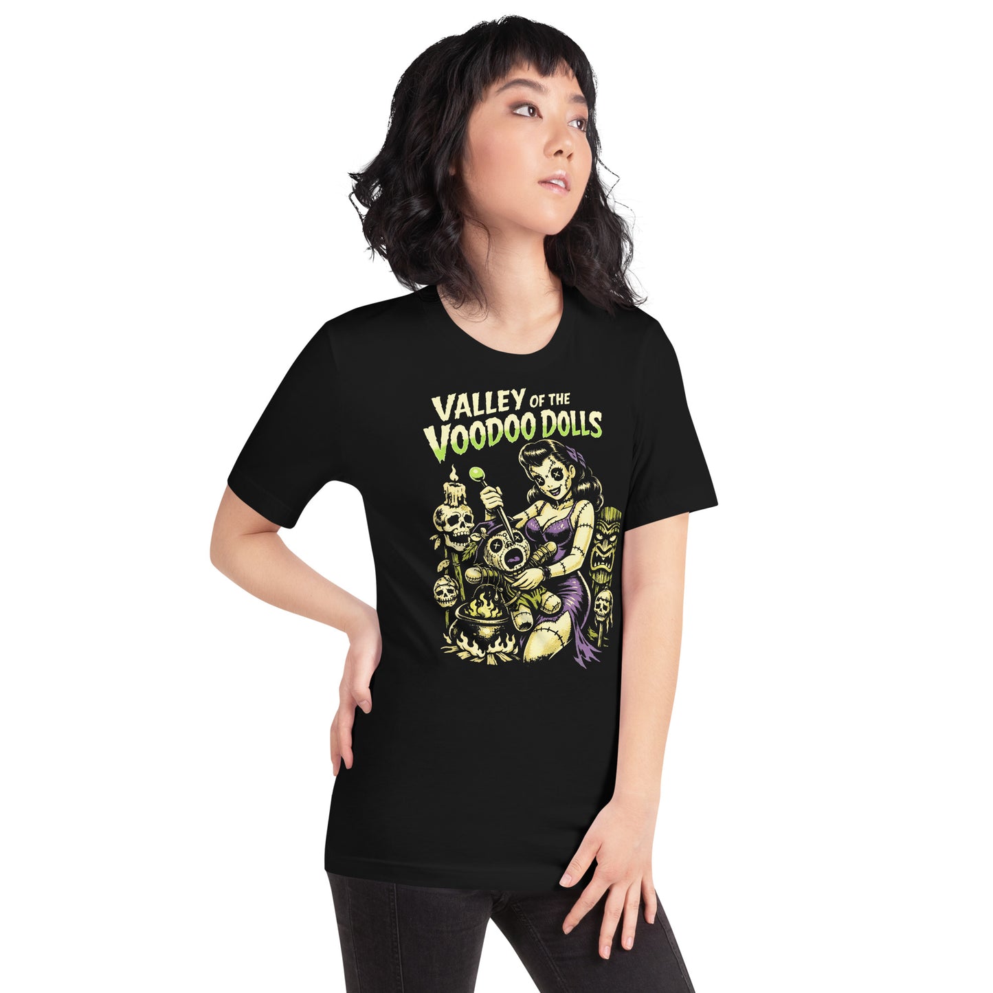 A retro-style graphic on a black t-shirt featuring a stylized pinup girl voodoo doll turning the tables on a medicine man in a vibrant, gritty Tiki-horror aesthetic