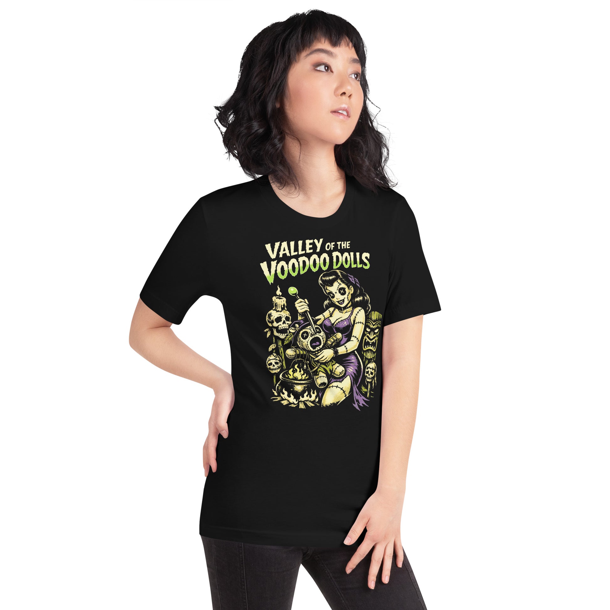 A retro-style graphic on a black t-shirt featuring a stylized pinup girl voodoo doll turning the tables on a medicine man in a vibrant, gritty Tiki-horror aesthetic