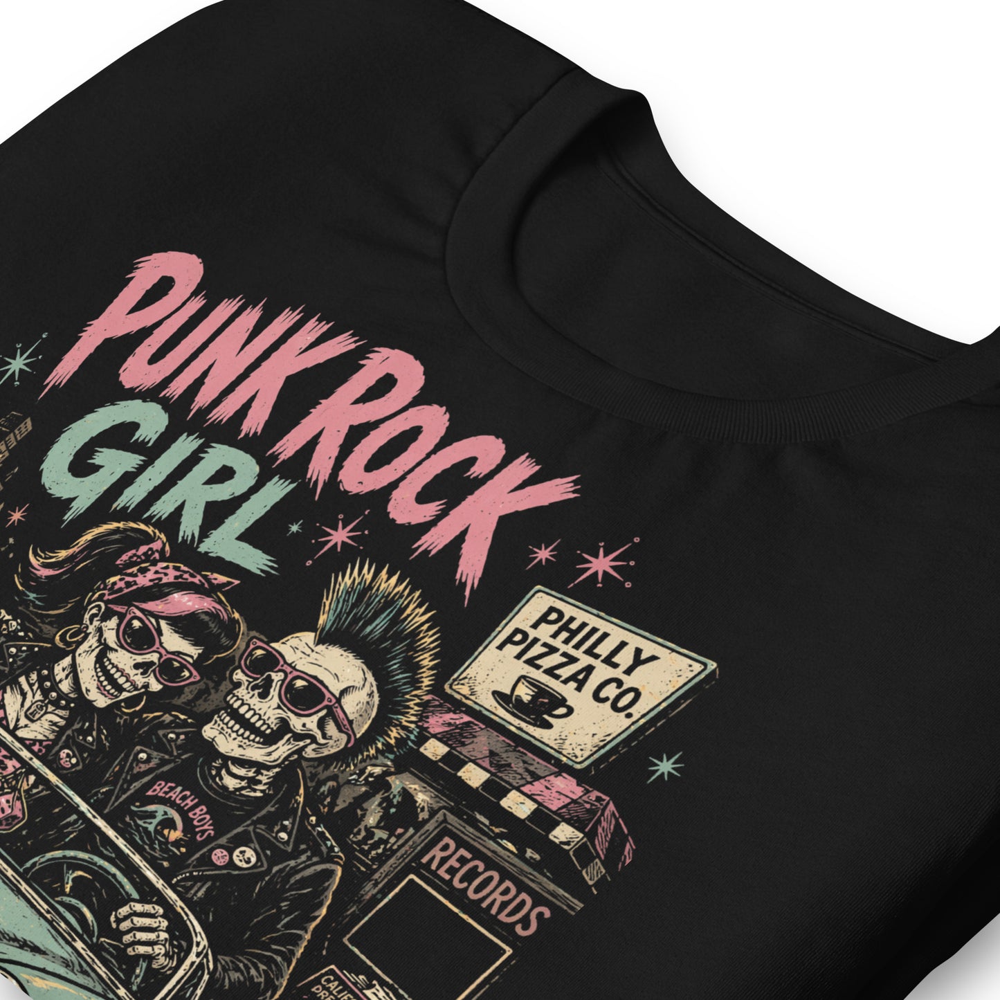 A retro-style graphic on a black t-shirt featuring two skeletons—a male with a mohawk and a female with a pink bow—driving a teal 1955 Chevy past iconic Philadelphia punk landmarks.