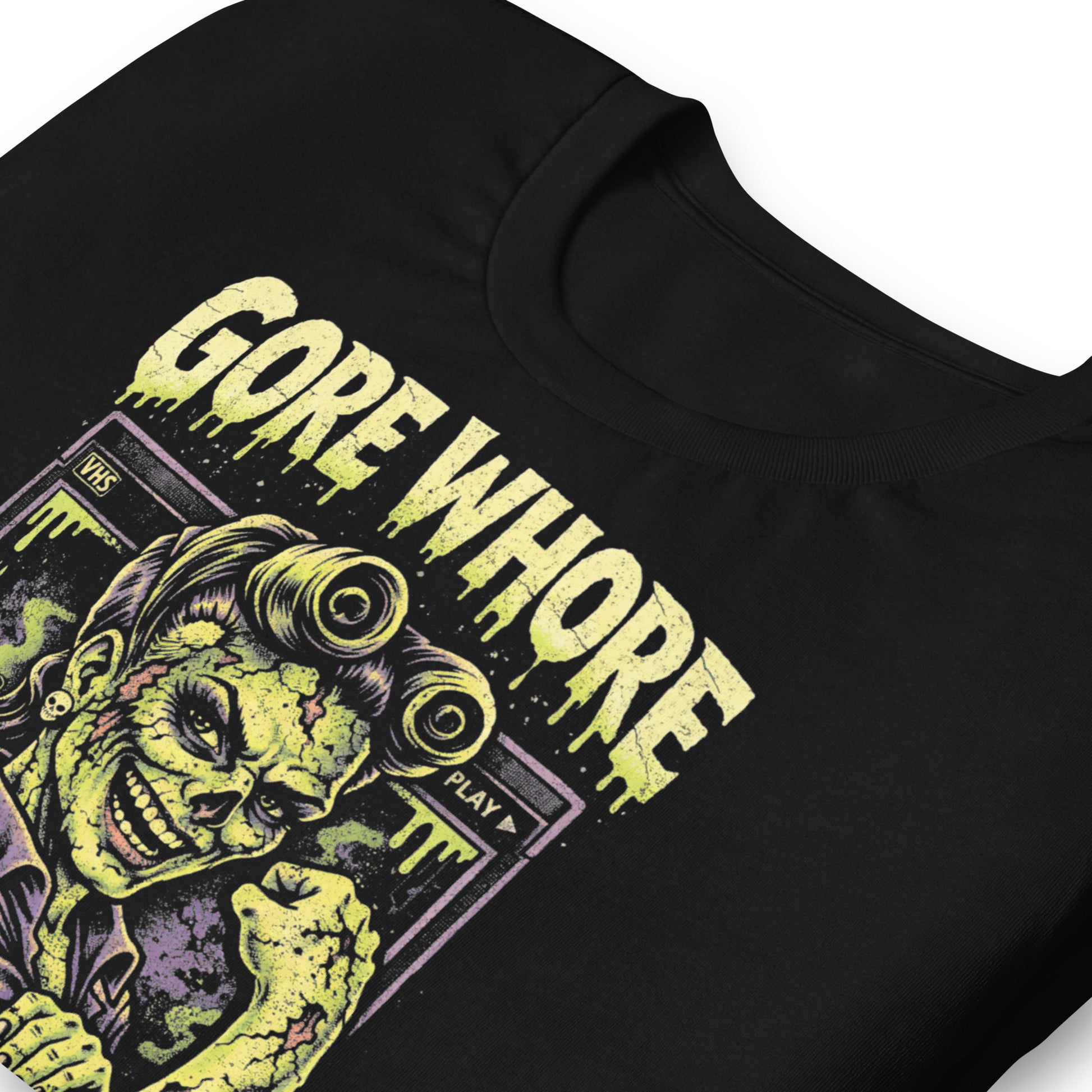A retro 80s horror-style graphic on a black t-shirt featuring a stylized zombie pin-up girl with "Gore Whore" and "Rotten to the Core" in distressed, slasher-flick lettering.