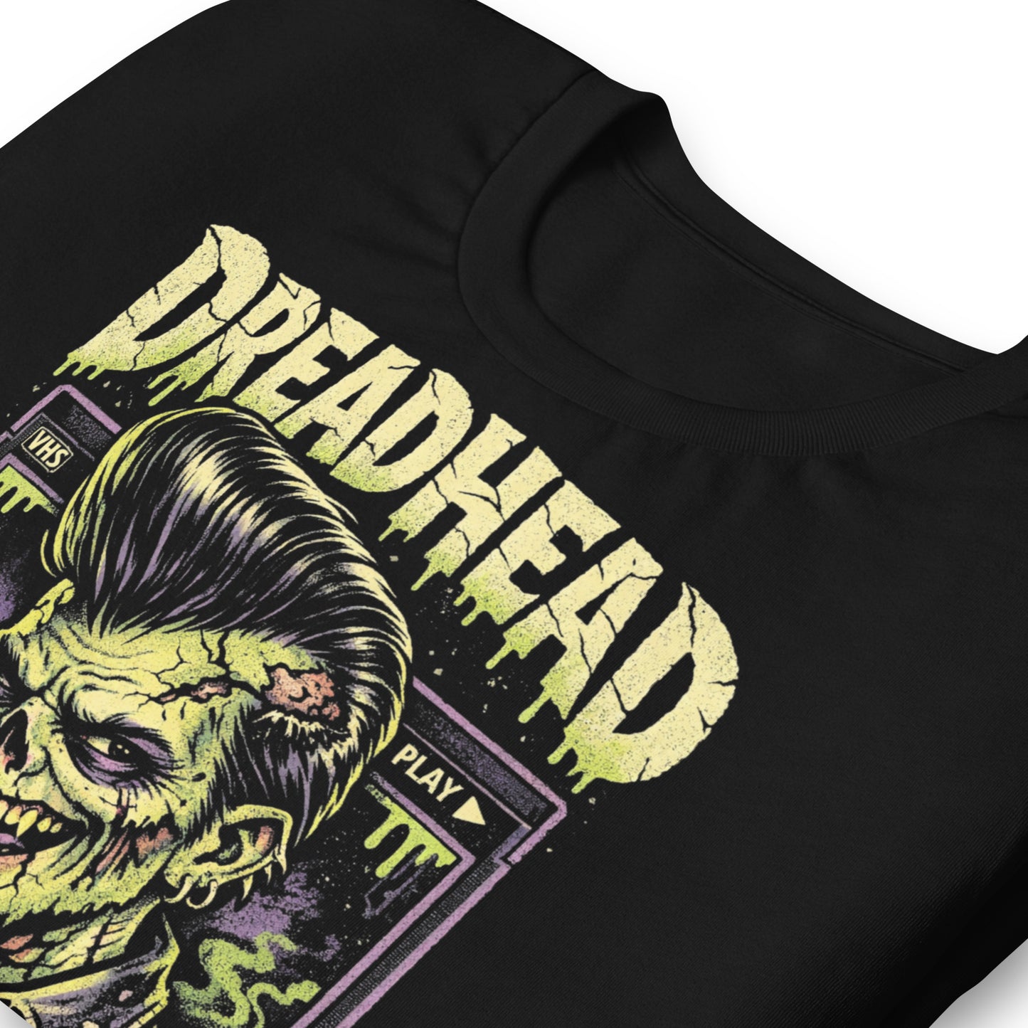 A retro 80s horror-style graphic on a black t-shirt featuring a zombie greaser with a pompadour and "Dreadhead" and "Rewind Repeat" in distressed VHS-style lettering.