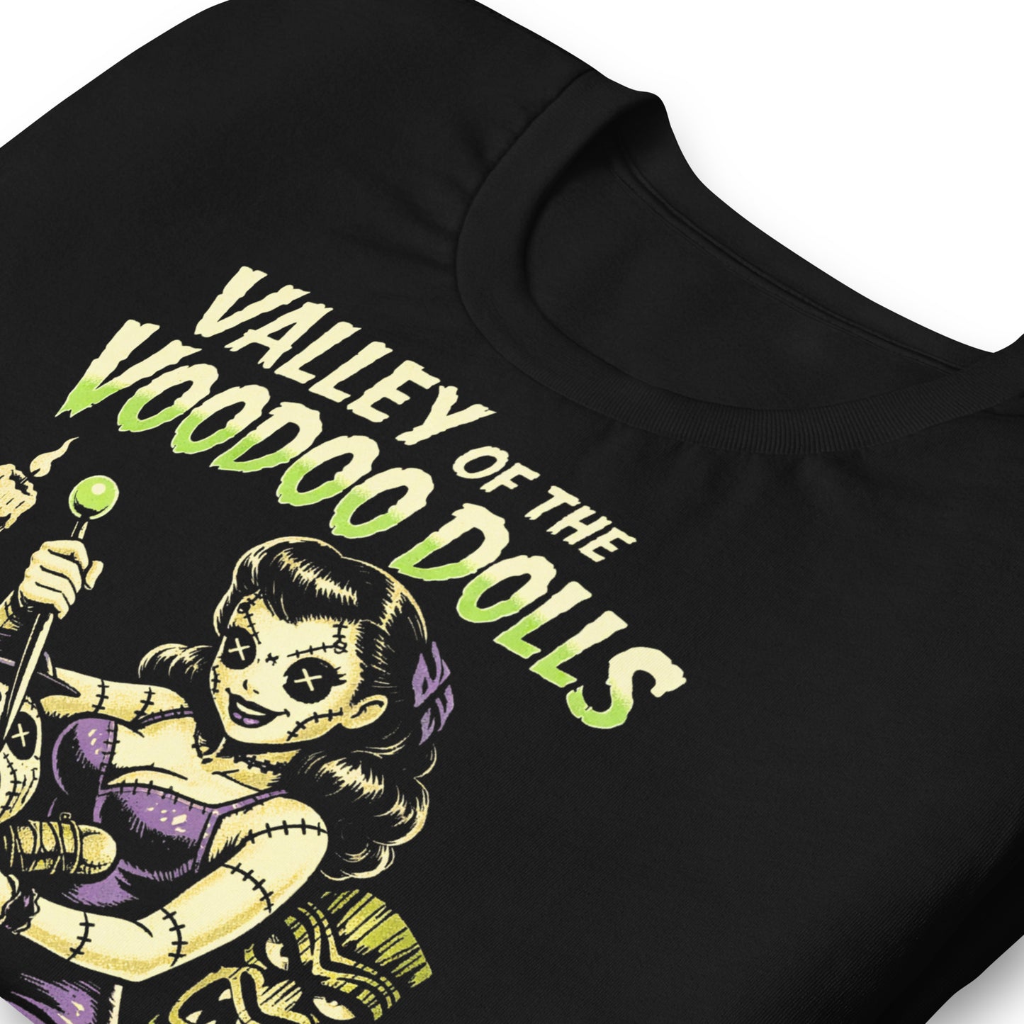 A retro-style graphic on a black t-shirt featuring a stylized pinup girl voodoo doll turning the tables on a medicine man in a vibrant, gritty Tiki-horror aesthetic