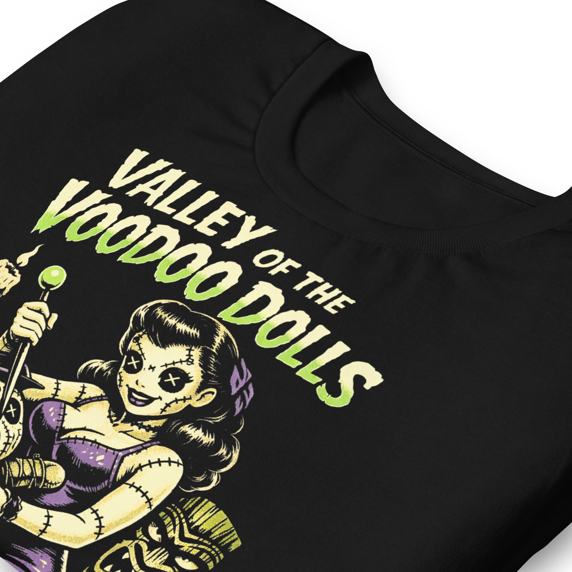 A retro-style graphic on a black t-shirt featuring a stylized pinup girl voodoo doll turning the tables on a medicine man in a vibrant, gritty Tiki-horror aesthetic