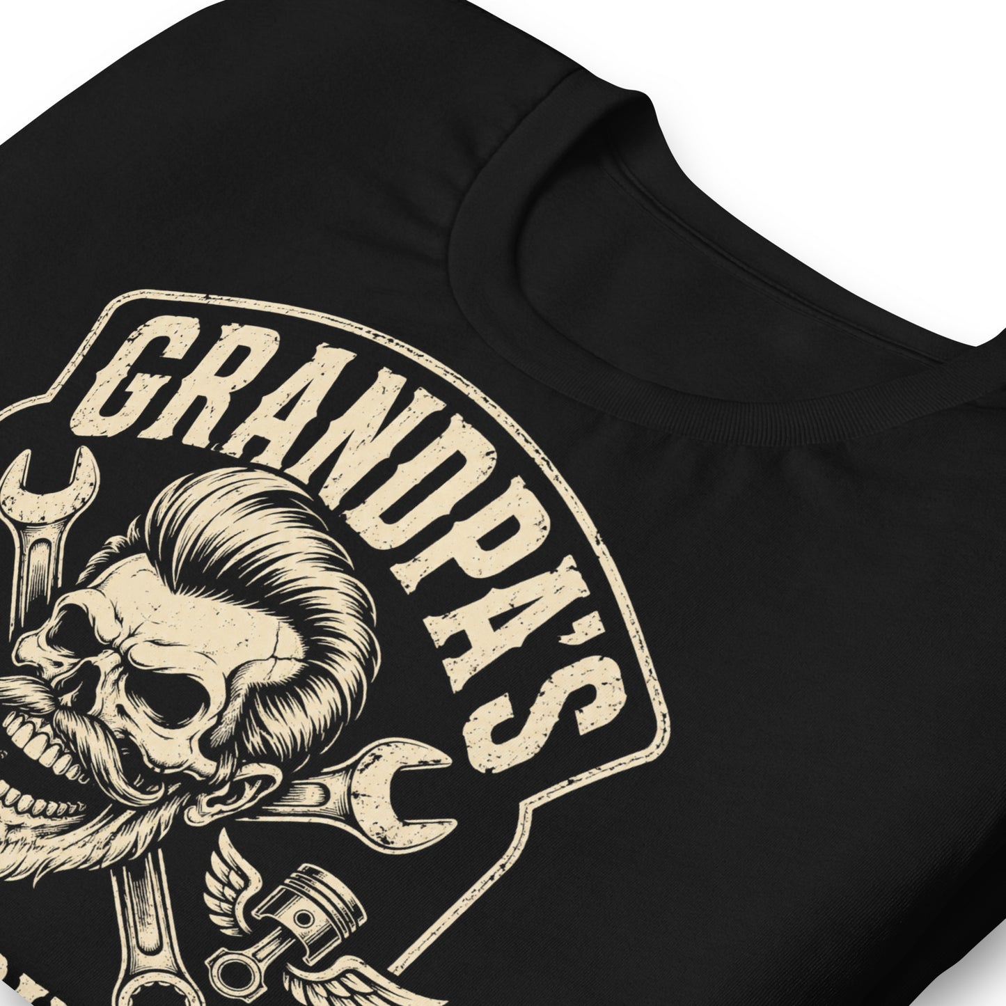 A black graphic tee featuring original Cinderpoint Studios artwork for Grandpa’s Speed Shop, a one-color retro garage design with a grinning skeletal grandpa, pompadour, mustache, crossed wrenches, winged pistons, flame accents, and No Refunds No Mercy text.