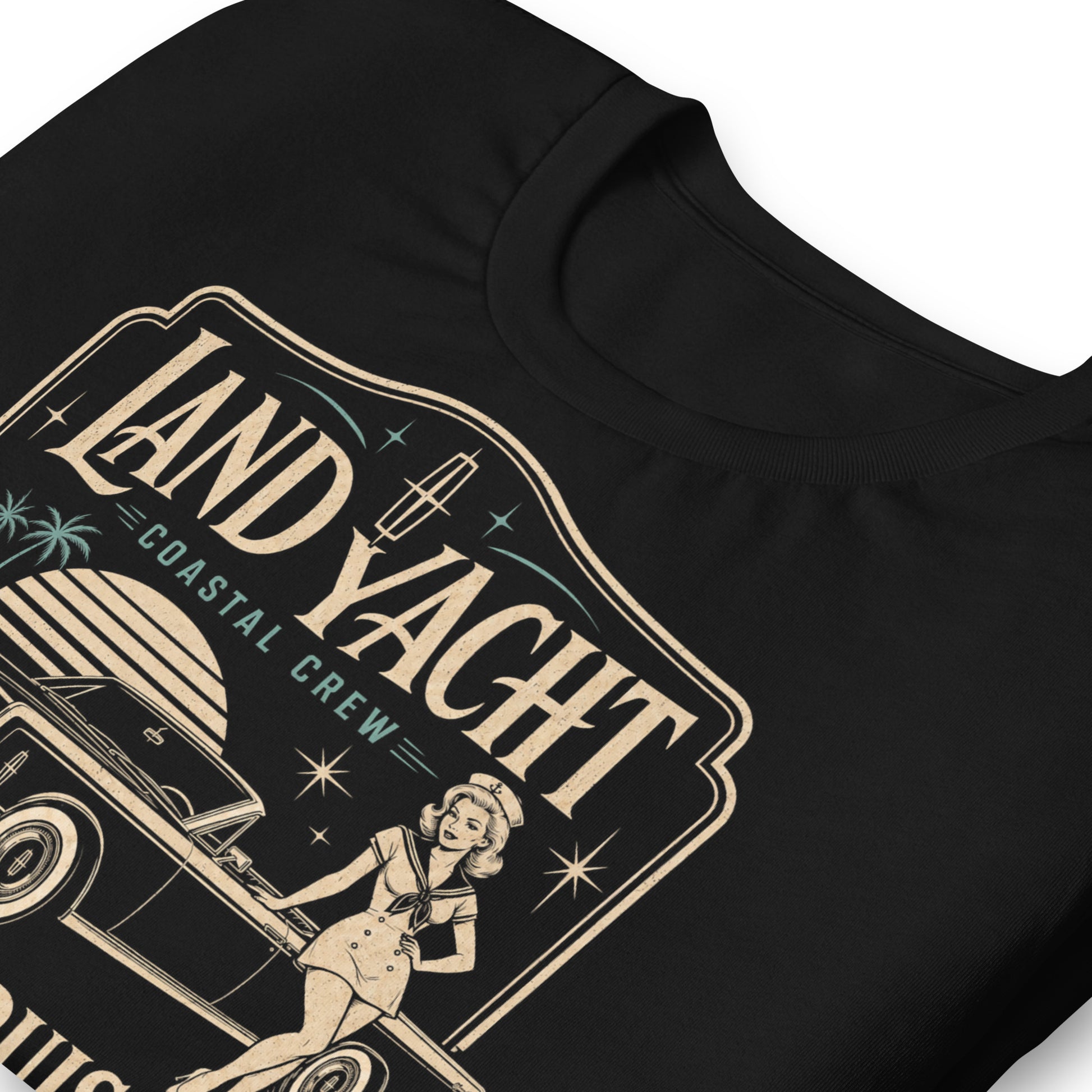 A black graphic tee featuring original Cinderpoint Studios artwork for Land Yacht Luxury Cruisers, a retro classic car design with a 1960s luxury convertible inspired by the 1965 Continental, a sailor pinup, atomic accents, palm trees, and bold vintage lettering.